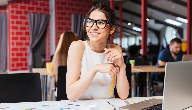 Mulher olhar sorridente em uma mesa com computador